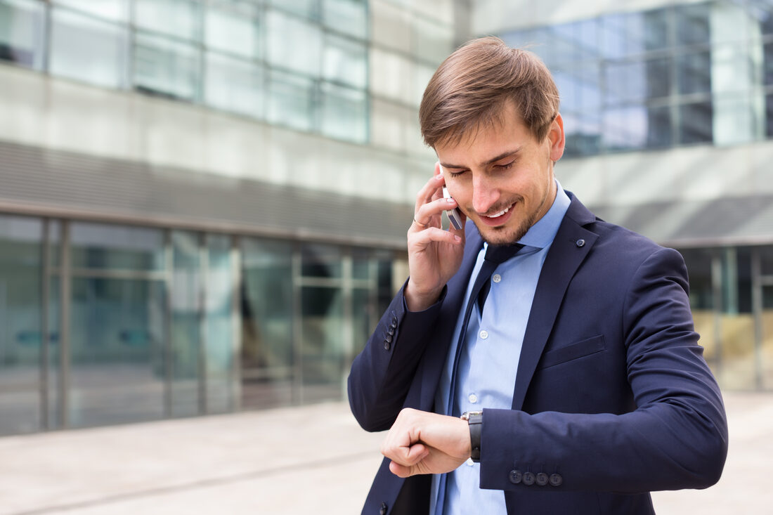 Ejecutivo revisando la hora mientras habla por teléfono